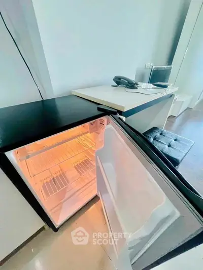 Compact kitchen area with open mini fridge and modern countertop.