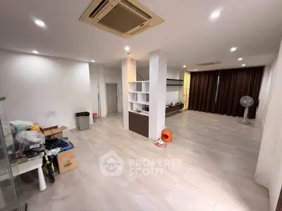 Spacious living room with modern design and ample natural light, featuring sleek tile flooring and built-in shelving.
