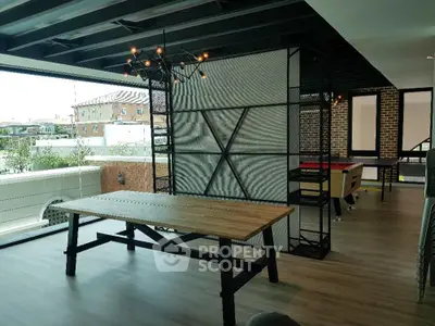 Spacious industrial-style loft with exposed brick walls and modern lighting, featuring a large dining table and an open floor plan.