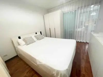 Cozy bedroom with modern decor and ample natural light, featuring a comfortable bed and stylish wardrobe.