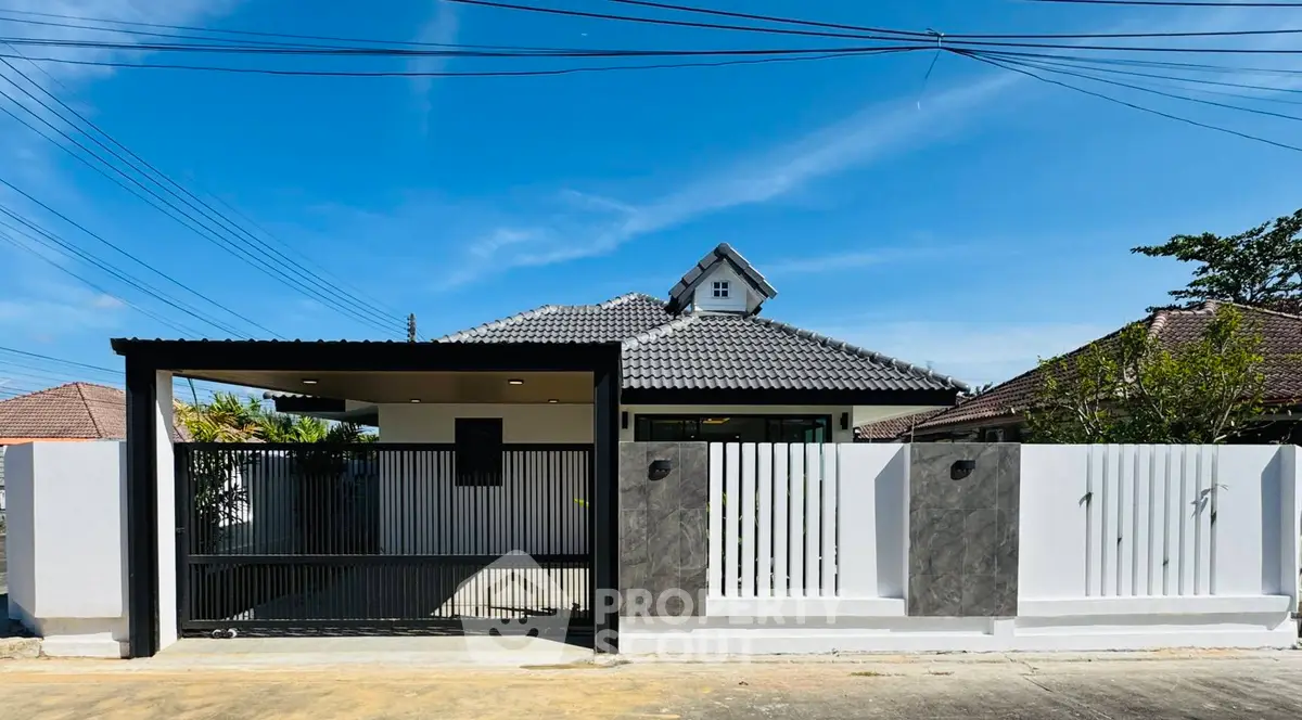 Modern single-story house with sleek gate and tiled roof under clear blue sky.