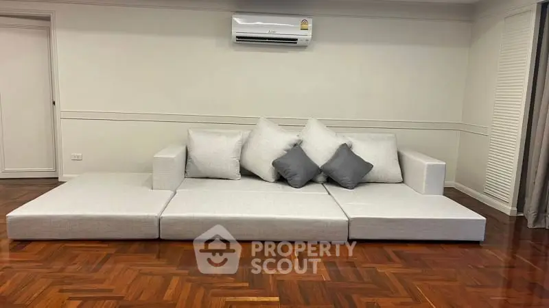 Modern living room with sleek sofa and air conditioning, featuring elegant wooden flooring.