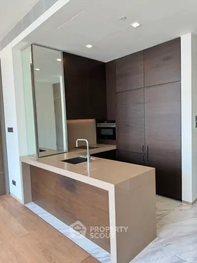 Modern kitchen with sleek design, featuring dark wood cabinets and integrated appliances.