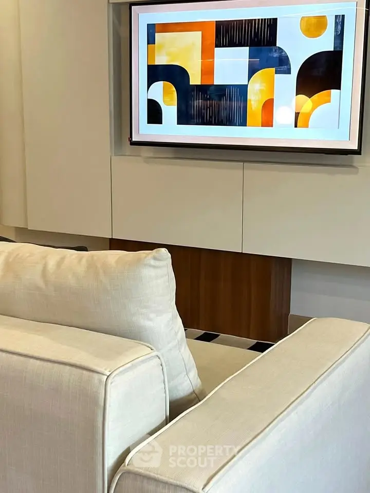Modern living room with stylish abstract art on TV screen and cozy beige sofas.