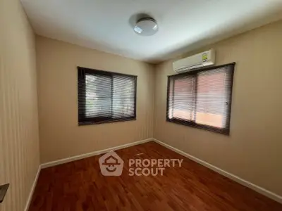 Spacious empty bedroom with wooden flooring and air conditioning