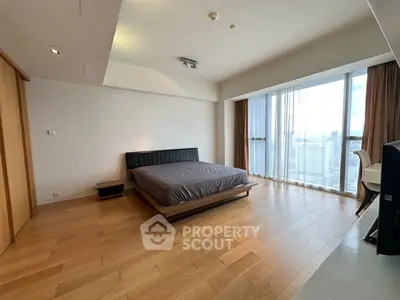 Spacious modern bedroom with large windows and wooden flooring