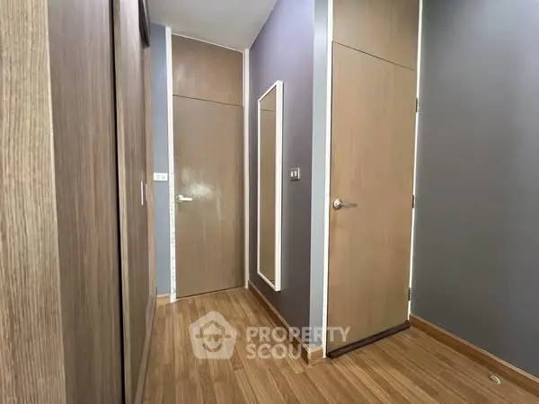 Modern hallway with wooden flooring and sleek doors in a contemporary apartment.