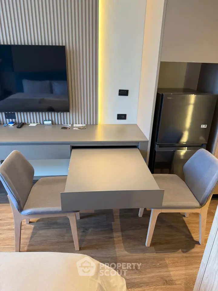 Modern apartment interior with sleek dining area and wall-mounted TV, featuring contemporary design and cozy ambiance.