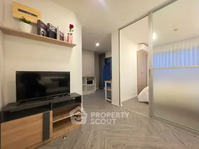 Modern living room with sleek design and open layout, featuring a TV and stylish shelving.