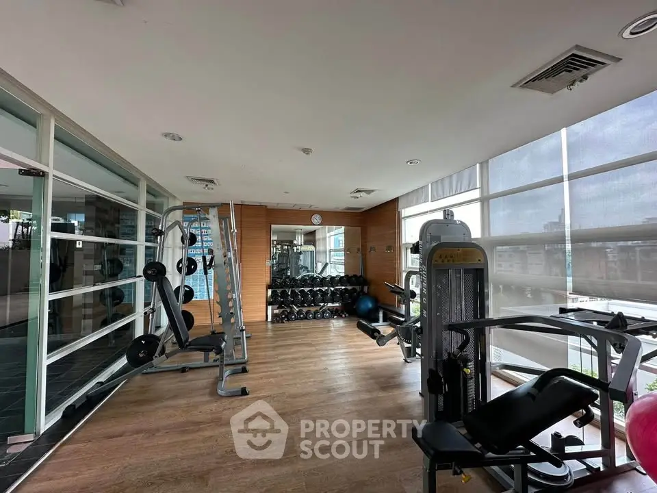 Modern gym with state-of-the-art equipment and large windows offering a bright workout space.