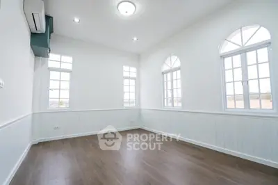 Spacious bright room with elegant arched windows and wooden flooring