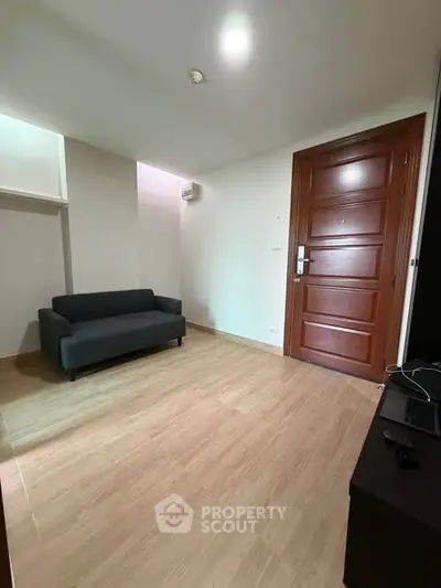 Spacious living room with modern sofa and wooden door, perfect for cozy living.