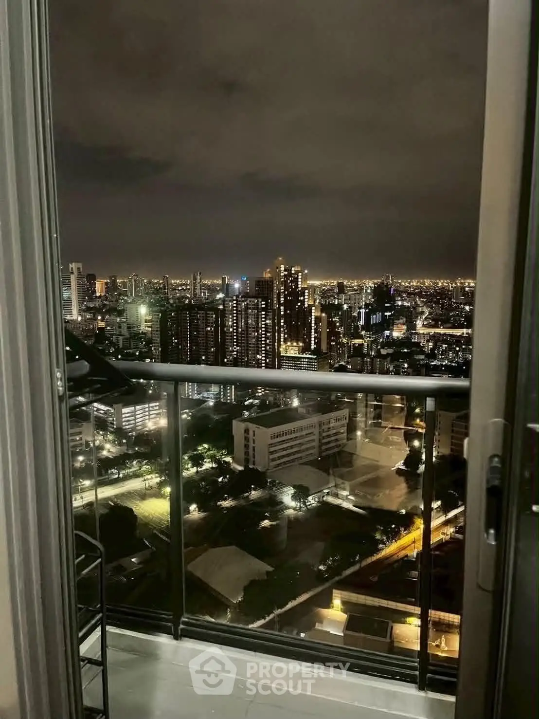 Stunning cityscape view from a high-rise balcony at night, showcasing urban skyline and twinkling lights.