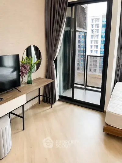 Modern bedroom with balcony view, stylish decor, and natural light in urban apartment.