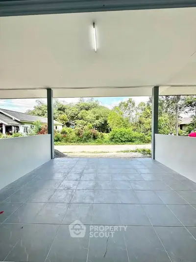Spacious covered patio with tiled flooring and scenic garden view, perfect for outdoor relaxation.