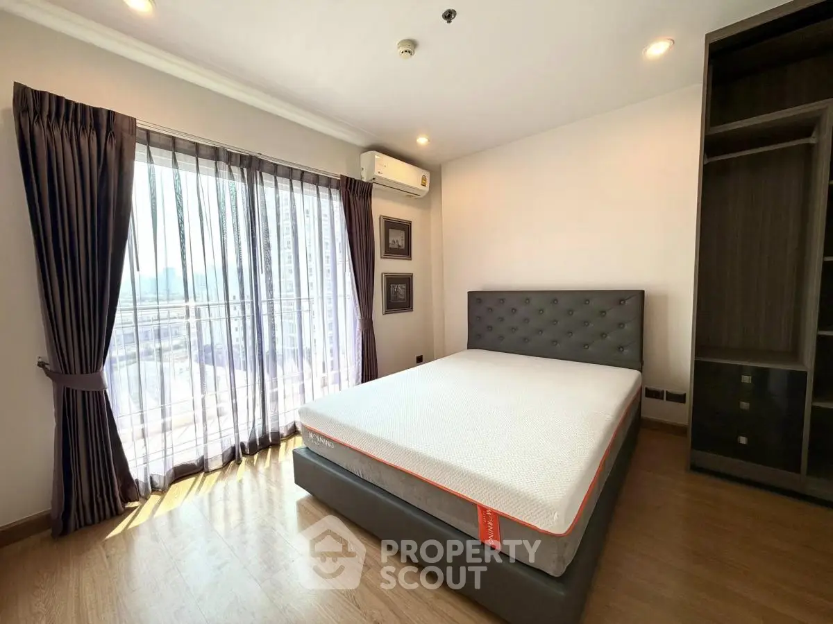 Spacious bedroom with modern decor and large window offering natural light.
