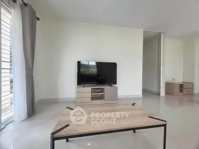 Spacious living room with modern TV setup and sleek coffee table, perfect for relaxation.