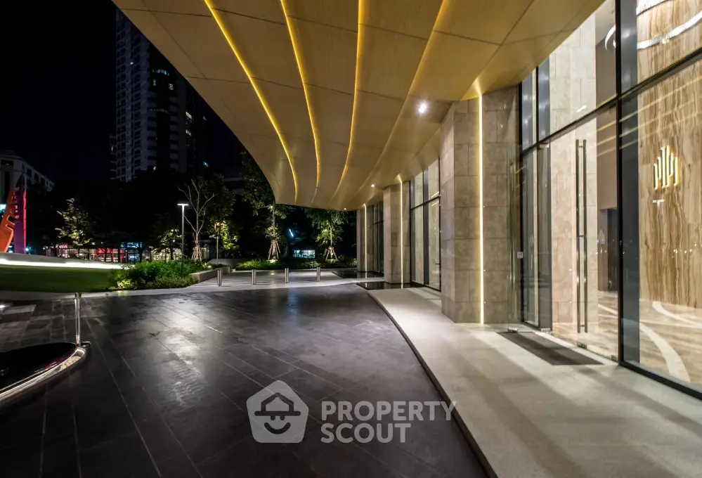 Luxurious modern building entrance with elegant lighting and sleek design at night.