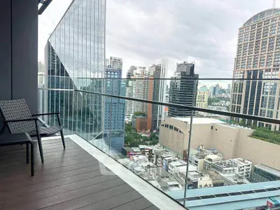 Stunning cityscape view from a modern balcony with sleek glass railing and cozy seating.