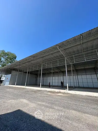 Spacious industrial warehouse with open layout and high ceilings under clear blue sky.