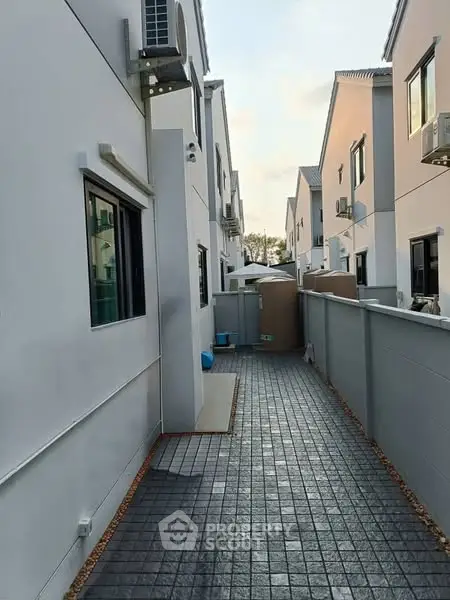 Modern townhouse exterior with paved walkway and white facade