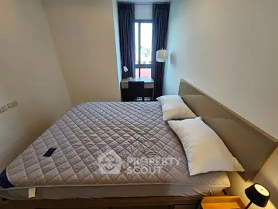 Cozy bedroom with large bed and window view, perfect for relaxation and comfort.