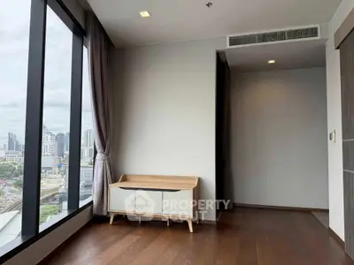 Modern apartment with large windows offering stunning city views and elegant wooden flooring.