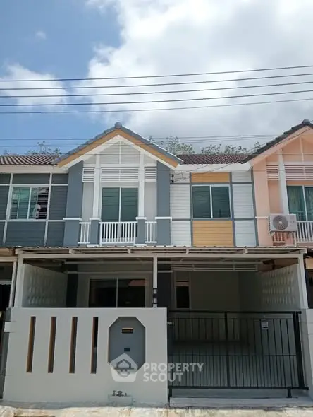 Charming townhouse with modern facade and gated entrance under a clear blue sky.