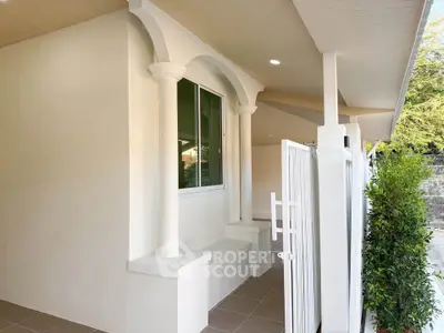 Charming exterior view of a modern home with elegant columns and lush greenery.