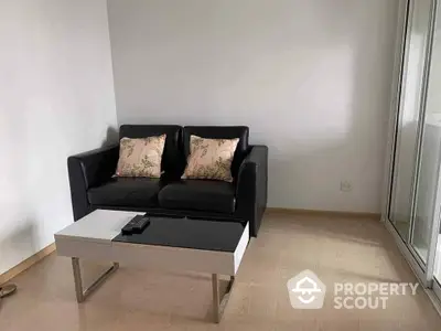 Minimalist living room with sleek black sofa and modern white coffee table, ample natural light from large window, perfect for urban living.