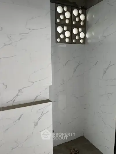 Modern bathroom with marble tiles and unique circular window design