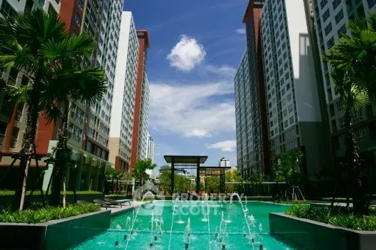 Luxurious apartment complex with stunning pool and lush greenery under a clear blue sky.