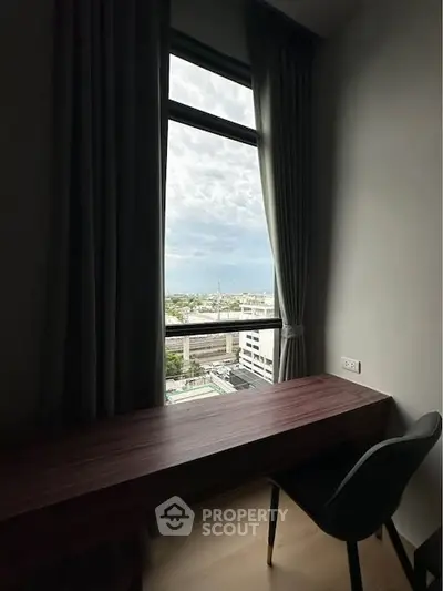 Modern study room with city view from large window, featuring sleek desk and chair.