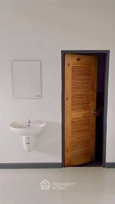 Minimalist bathroom with wooden door and wall-mounted sink