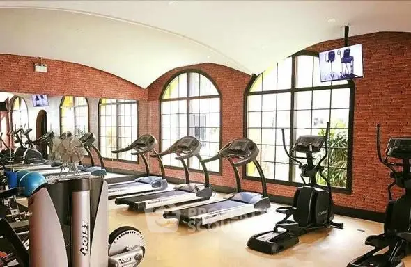 Spacious gym with modern equipment and large windows in luxury property