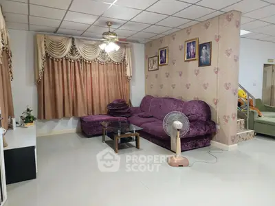 Spacious living room with plush purple sofa and elegant curtains, perfect for family gatherings.