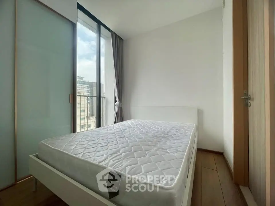 Bright and airy bedroom with large window and modern design in urban apartment.