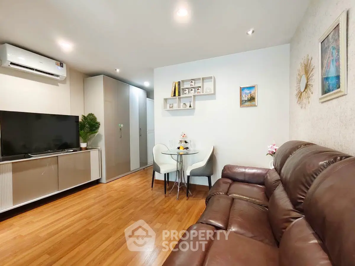Modern living room with leather sofa, TV, and dining area in stylish apartment.