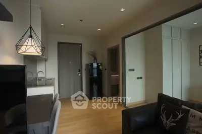 Modern open-plan living room with stylish lighting and sleek kitchen area.