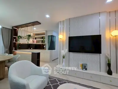 Modern living room with elegant decor and open layout, featuring a large TV and stylish furniture.