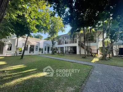 Charming two-story white building with lush garden and pathway, perfect for serene living.
