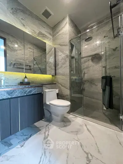 Luxurious modern bathroom with marble tiles and glass shower enclosure