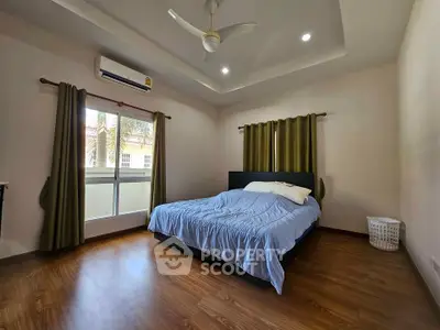 Spacious bedroom with modern ceiling fan and natural light, perfect for relaxation.