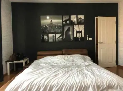 Modern bedroom with stylish wall art and cozy bed in contemporary apartment.