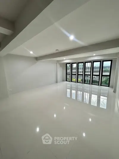 Spacious modern living room with large windows and glossy white flooring.