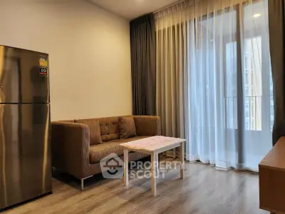 Modern living room with cozy sofa, sleek fridge, and floor-to-ceiling windows for natural light.