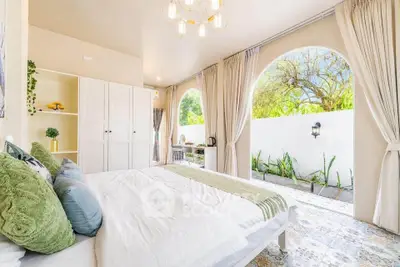 Luxurious bedroom with elegant decor and garden view, featuring large windows and stylish furnishings.