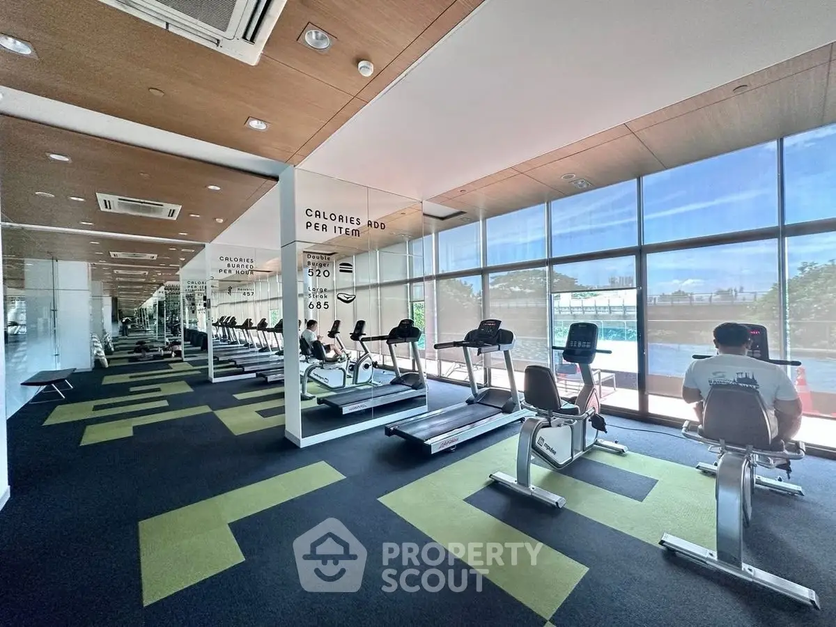 Modern gym with exercise bikes and large windows overlooking a pool area, perfect for fitness enthusiasts.