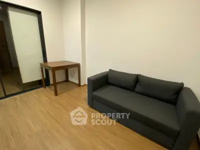 Modern living room with sleek black sofa and wooden table on elegant wooden flooring.