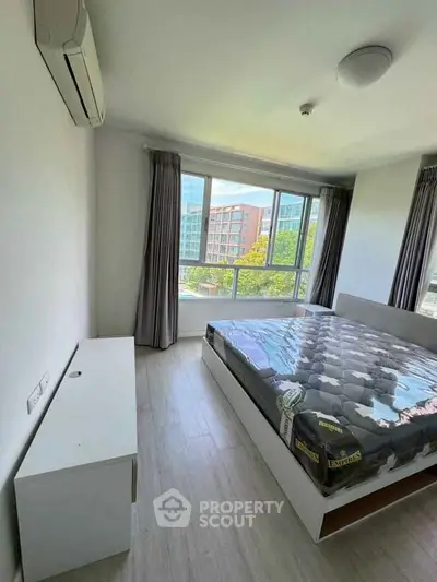 Bright bedroom with large window and modern furnishings in a high-rise apartment.